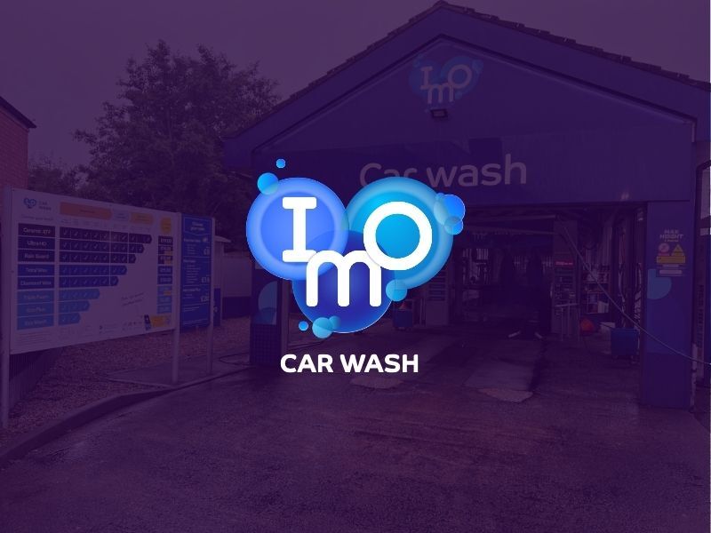 IMO Car Wash entrance with logo and pricing board in front of the wash bay