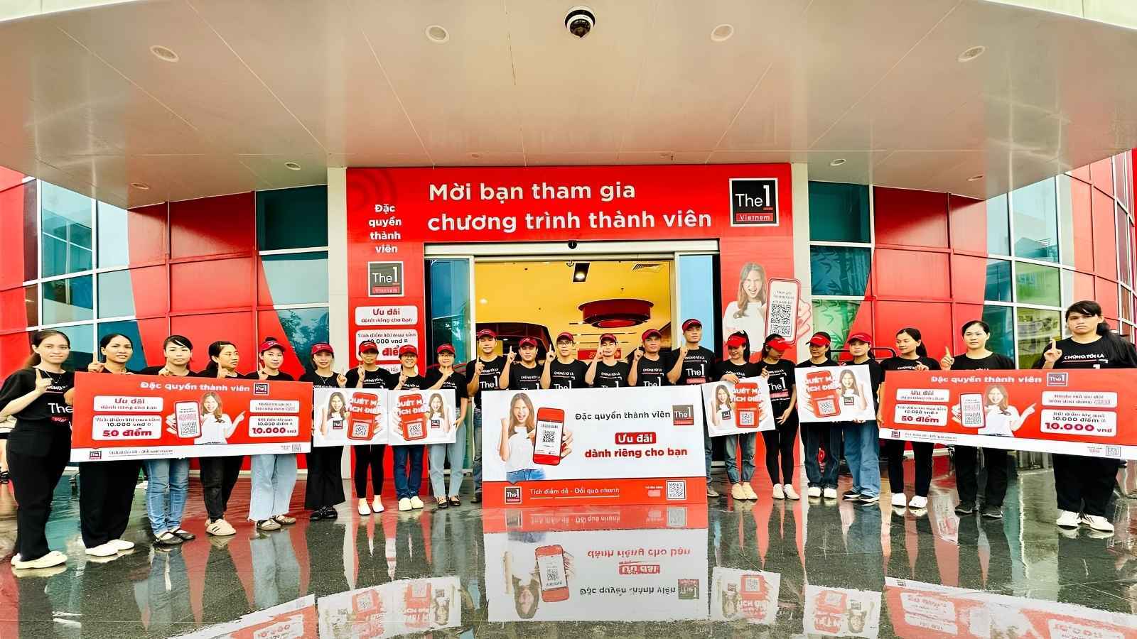 Central Retail Vietnam staff standing in front of a store entrance holding promotional posters for The 1 Vietnam loyalty program.