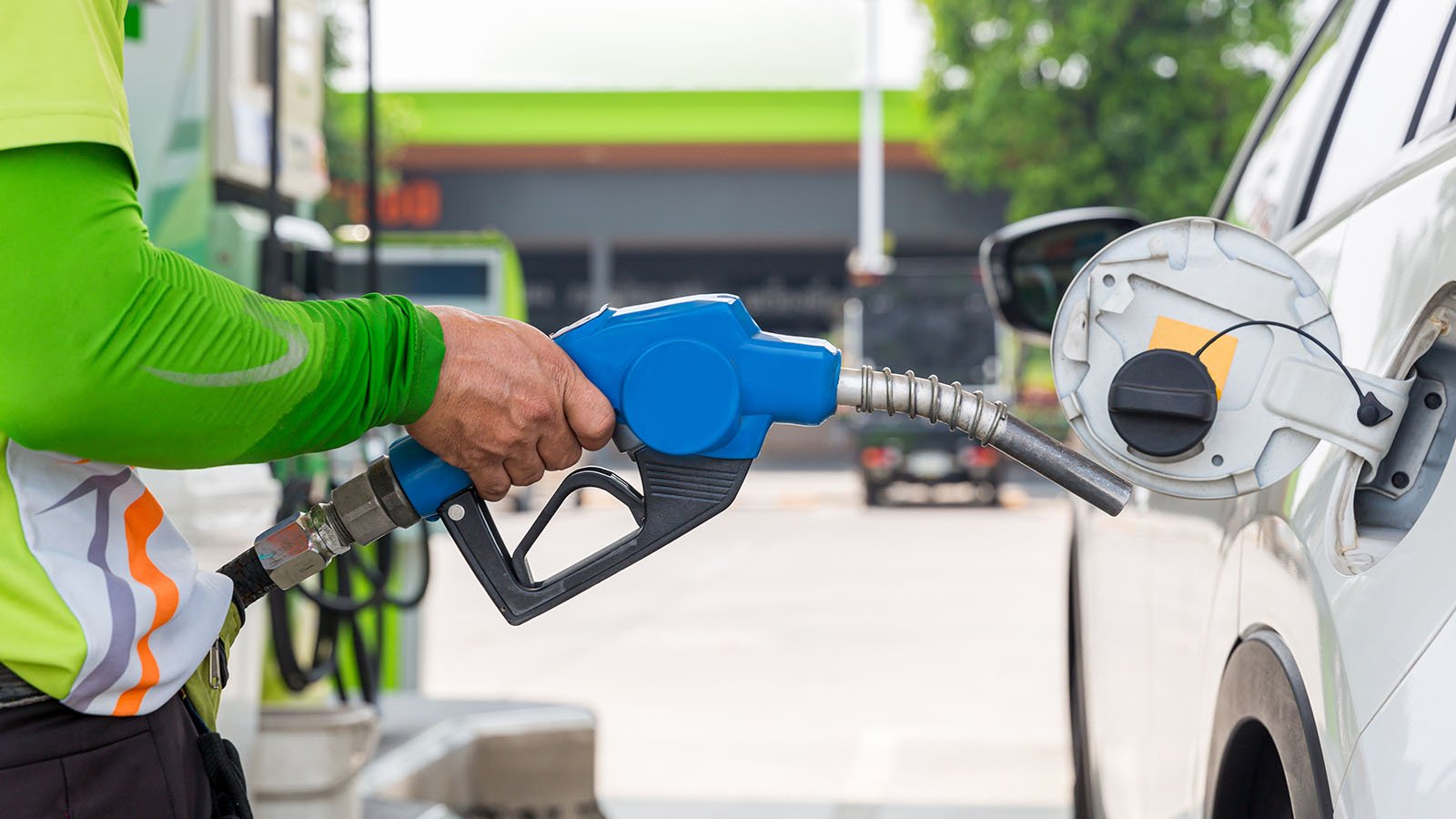 Hand holding gas nozzle with one last drop. A man holding a gasoline nozzle.