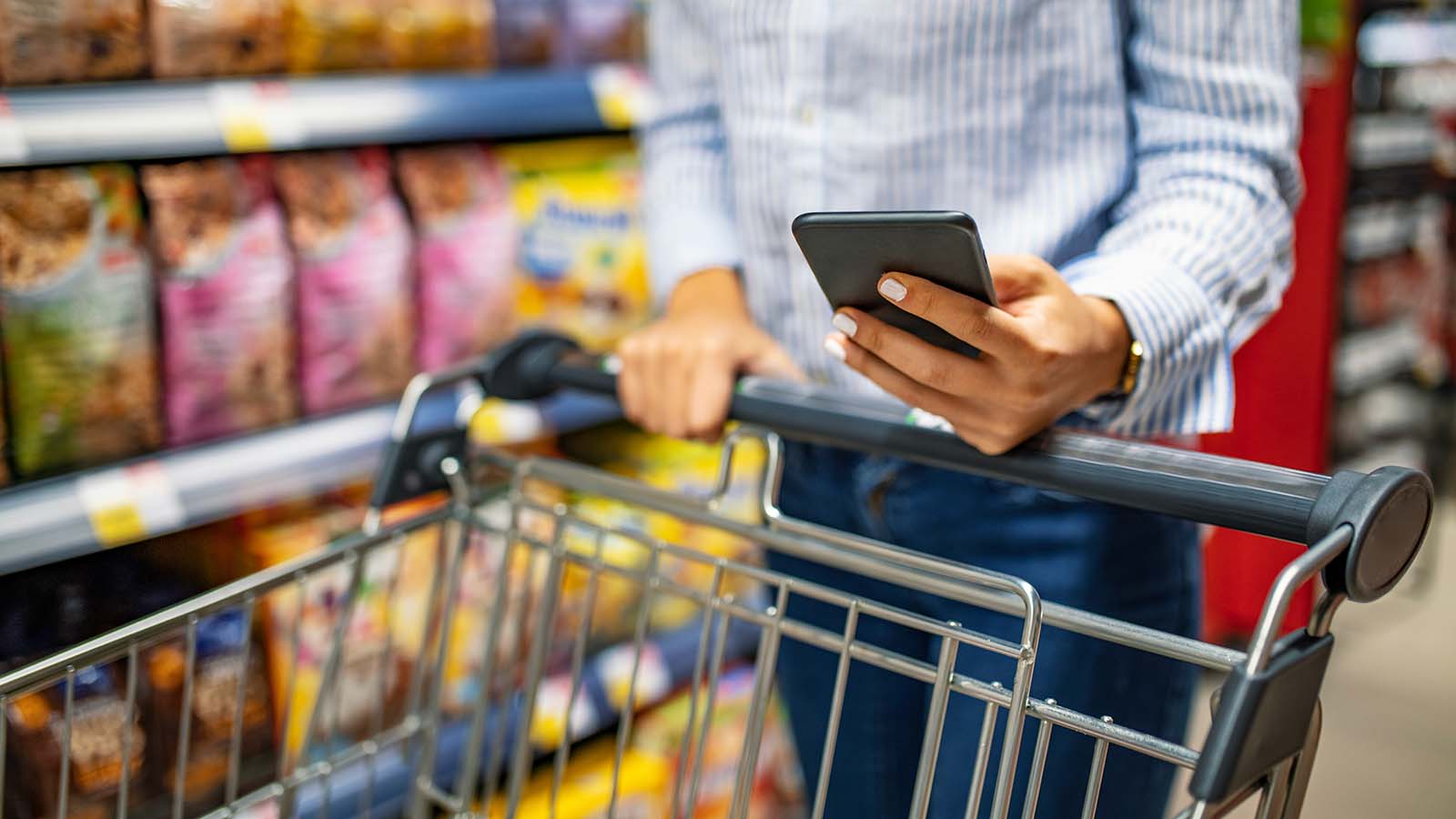 Woman with smartphone in store grocery shopping